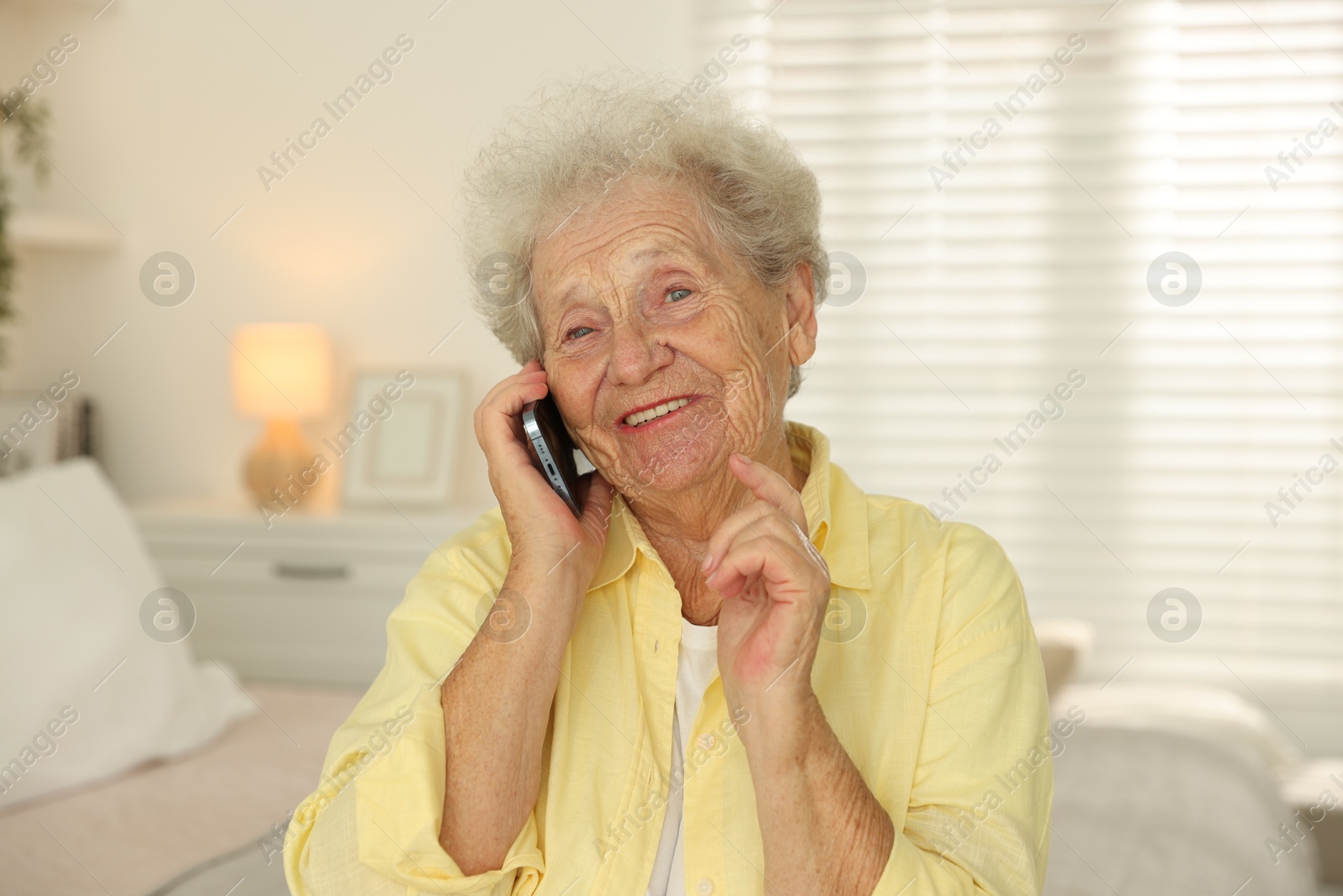 Photo of Smiling senior woman talking on smartphone at home