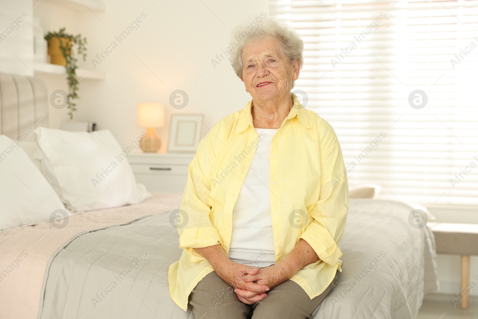 Photo of Beautiful senior woman sitting on bed at home