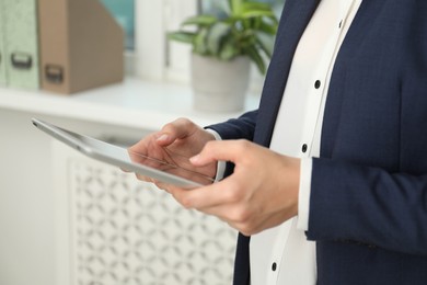 Photo of Businesswoman using tablet indoors, closeup. Modern technology