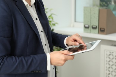 Photo of Businesswoman using tablet indoors, closeup. Modern technology