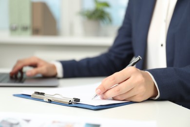 Photo of Businesswoman working at white table indoors, closeup view