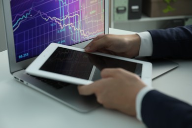 Photo of Businesswoman using tablet at white table indoors, closeup. Modern technology