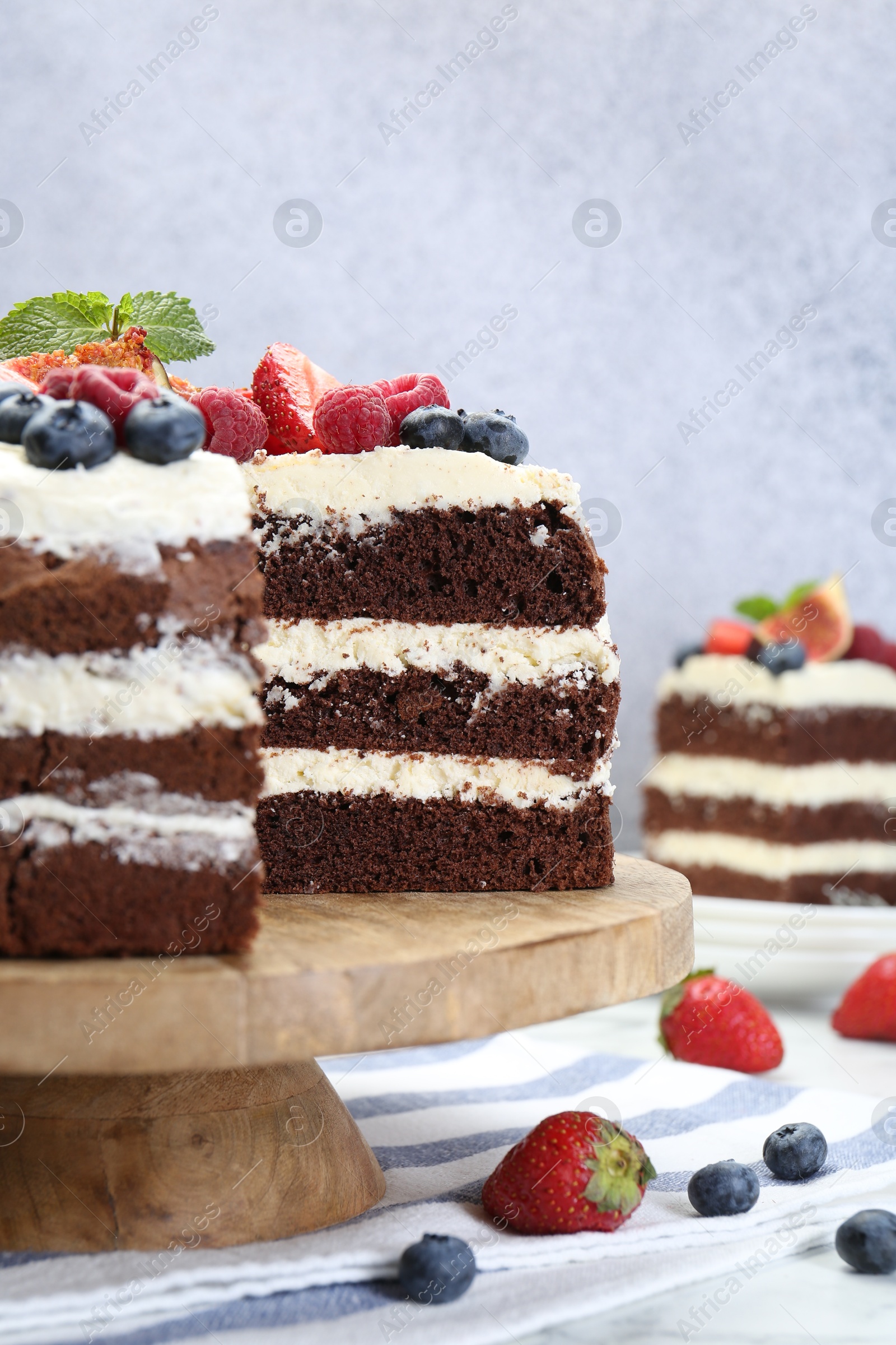 Photo of Delicious chocolate sponge cake with berries served on white table