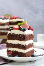 Photo of Piece of delicious chocolate sponge cake with berries served on white table