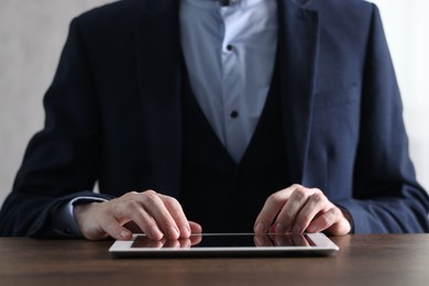 Photo of Businessman using tablet at wooden table, closeup. Modern technology