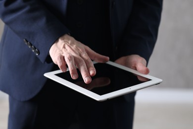 Photo of Businessman using tablet indoors, closeup. Modern technology