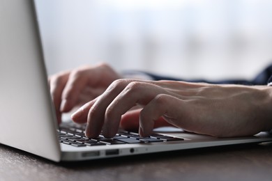 Photo of Businessman using laptop at table indoors, closeup. Modern technology