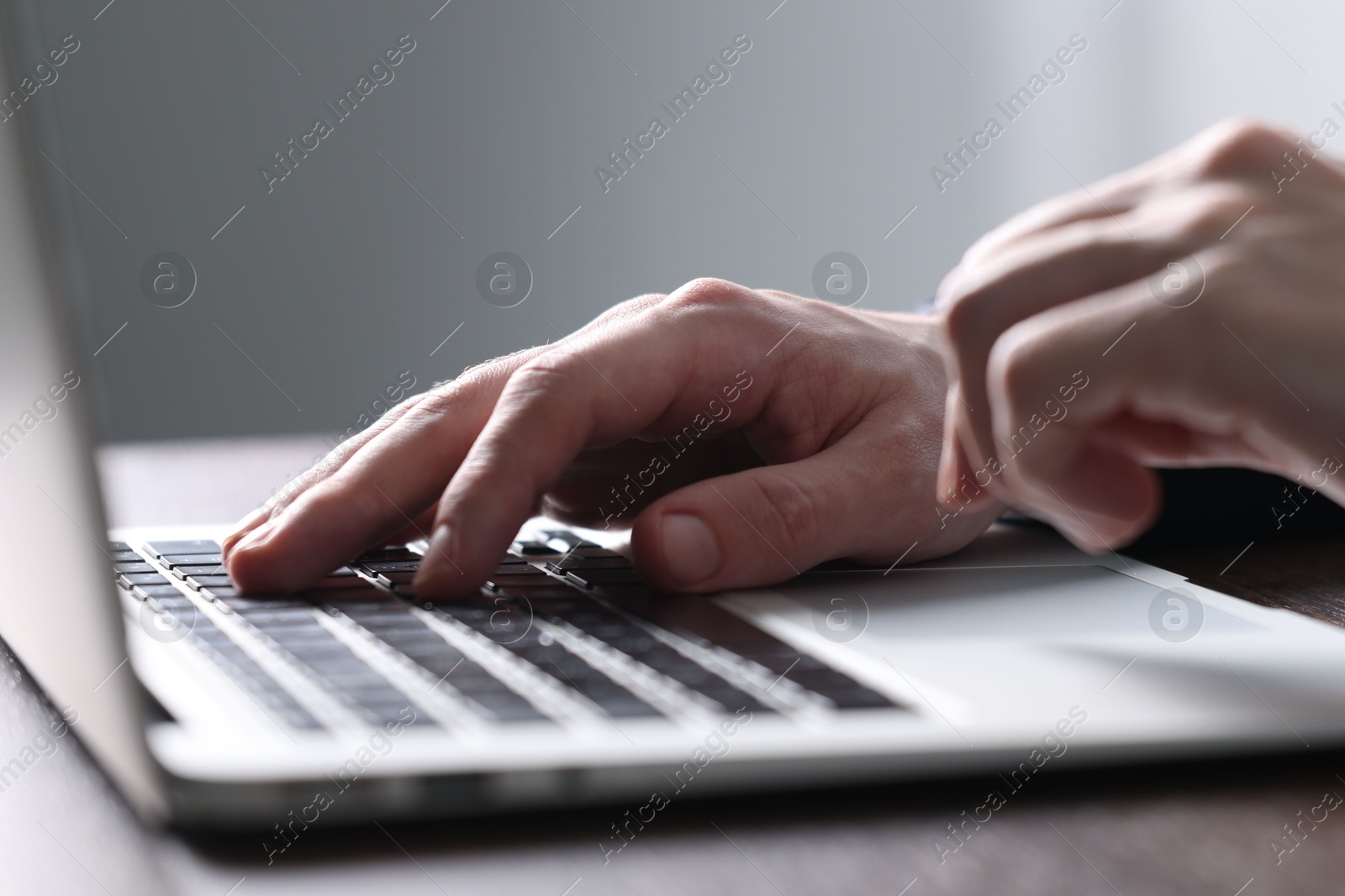 Photo of Businessman using laptop at table indoors, closeup. Modern technology