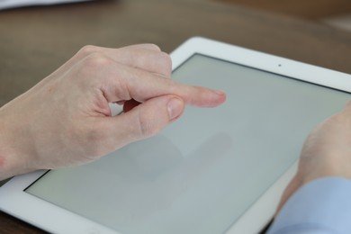 Photo of Businessman using tablet at table indoors, closeup. Modern technology