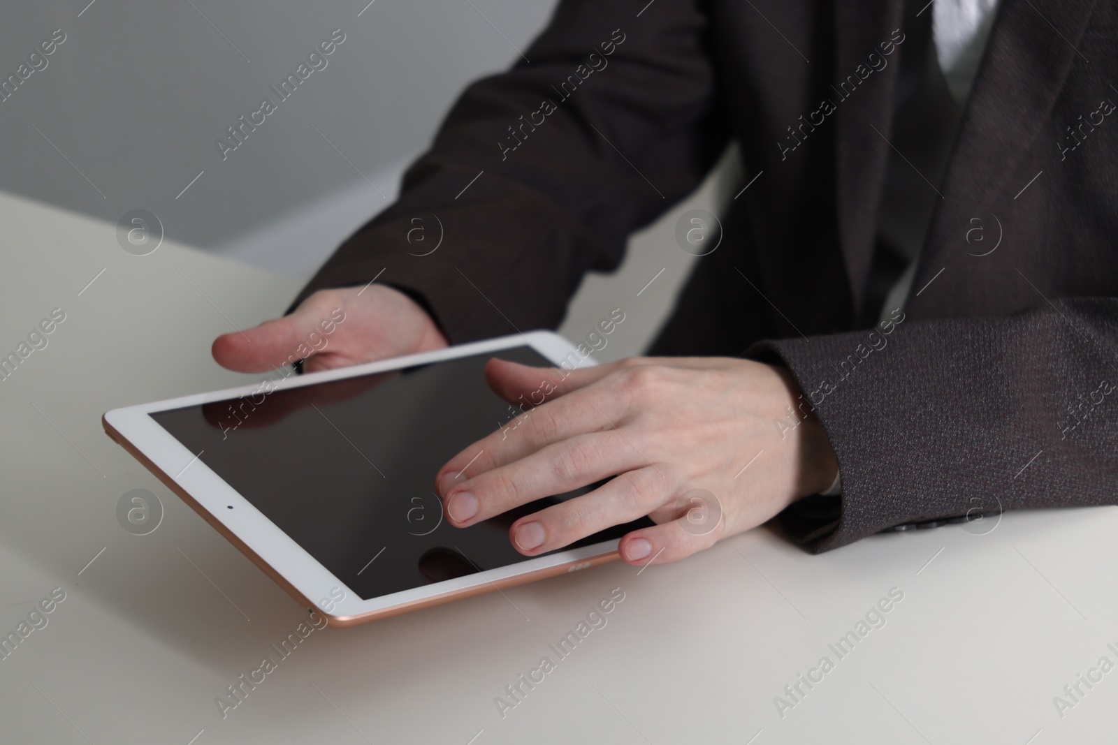 Photo of Businessman using tablet at white table indoors, closeup. Modern technology