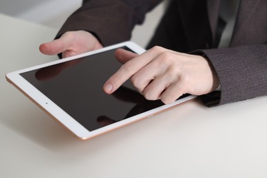 Photo of Businessman using tablet at white table indoors, closeup. Modern technology