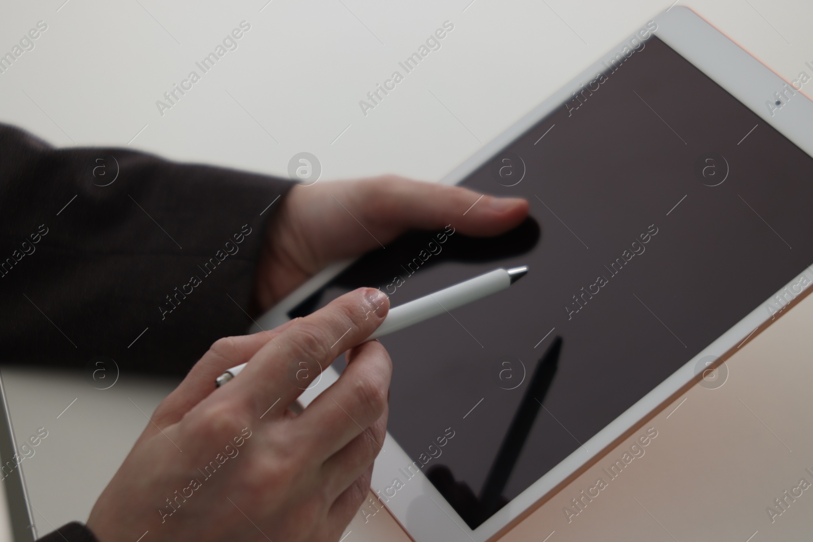 Photo of Businessman using tablet at white table, closeup. Modern technology