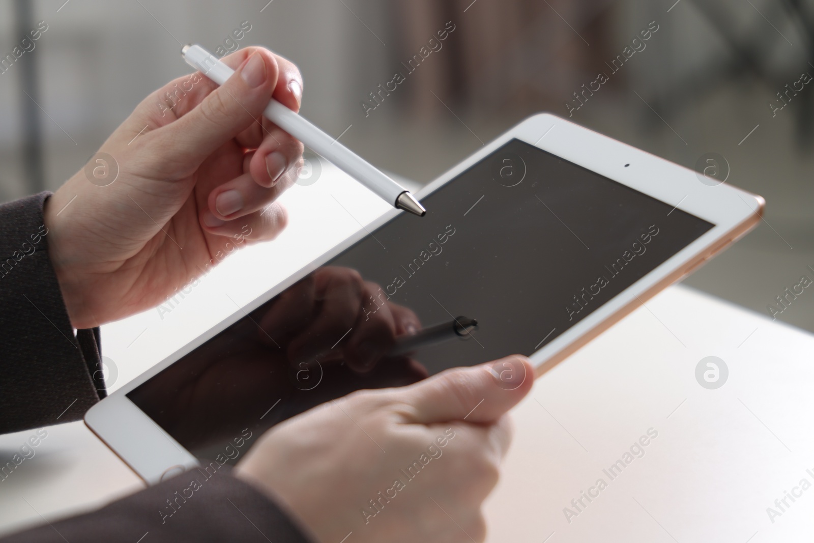 Photo of Businessman using tablet at white table indoors, closeup. Modern technology