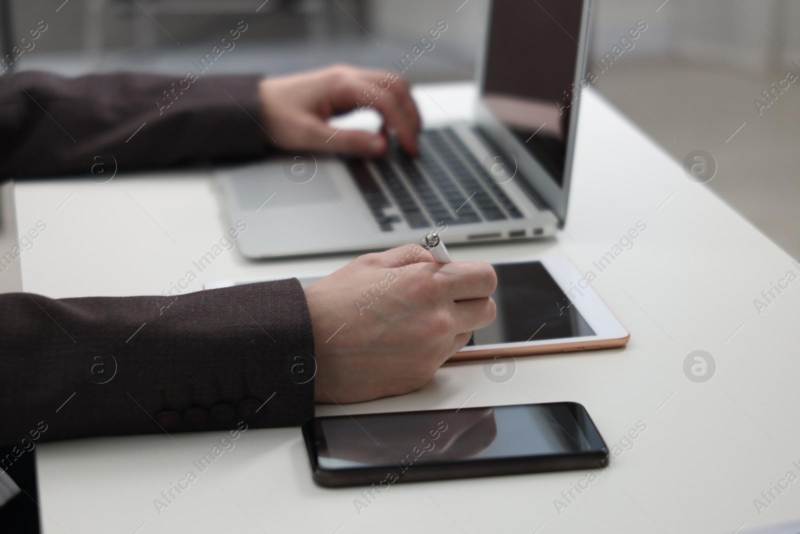 Photo of Businessman using different devices at white table indoors, closeup. Modern technology