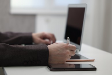 Photo of Businessman using different devices at white table indoors, closeup. Modern technology