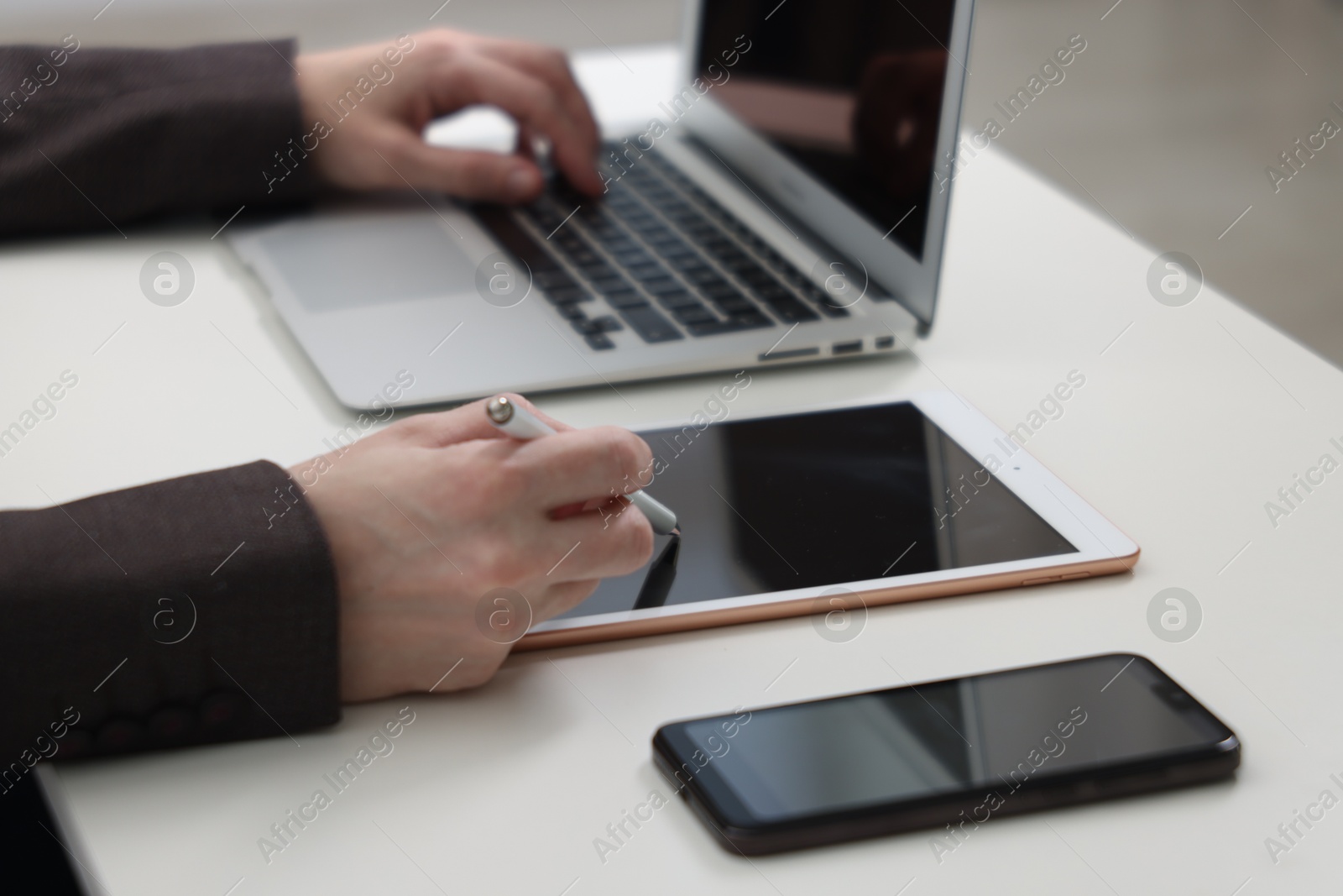 Photo of Businessman using different devices at white table indoors, closeup. Modern technology