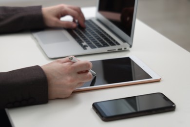 Photo of Businessman using different devices at white table indoors, closeup. Modern technology