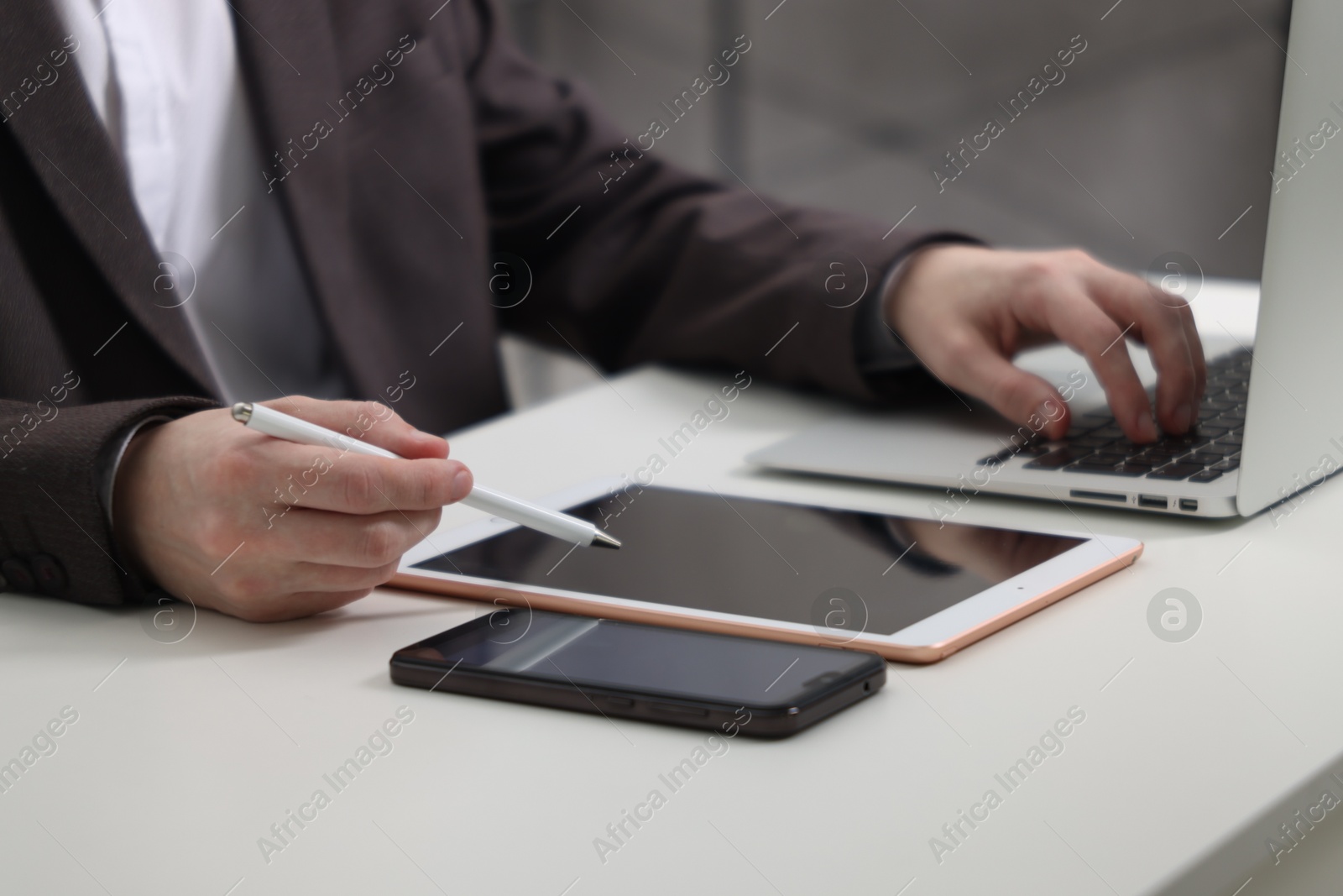 Photo of Businessman using different devices at white table indoors, closeup. Modern technology