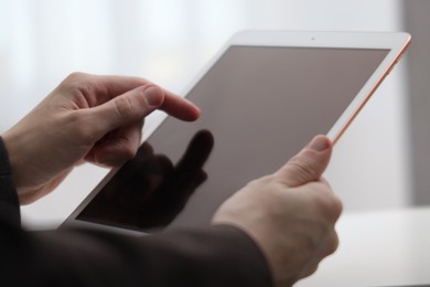 Photo of Businessman using tablet on blurred background, closeup. Modern technology