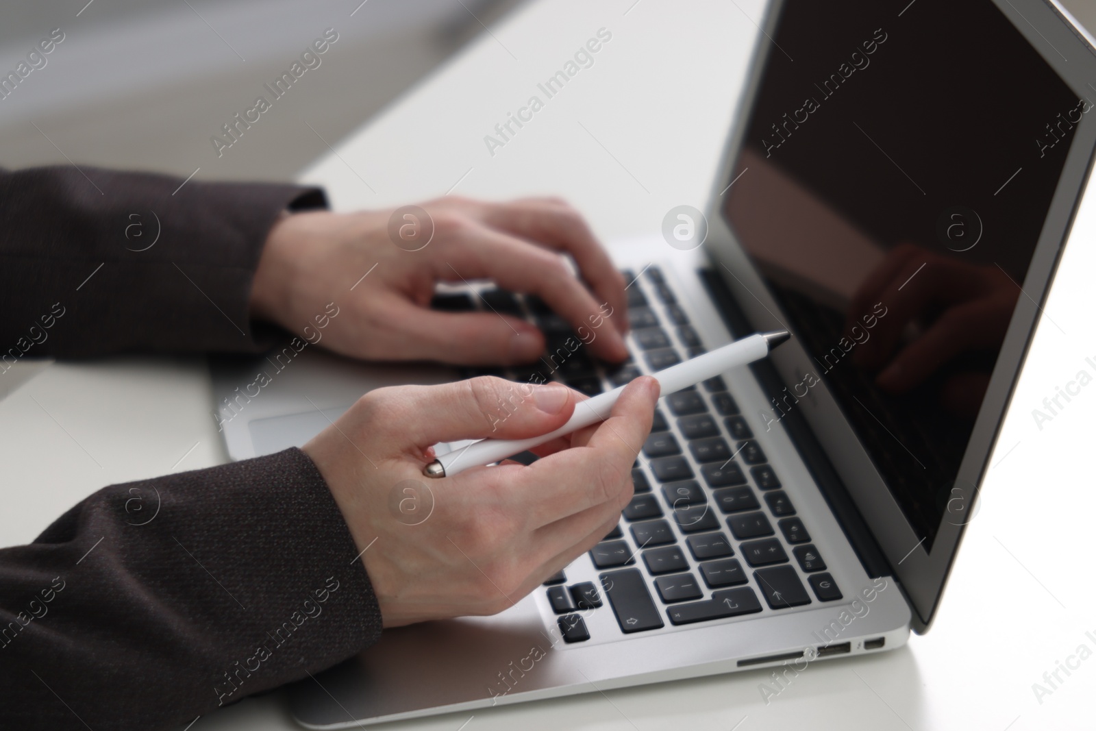 Photo of Businessman using laptop at white table indoors, closeup. Modern technology