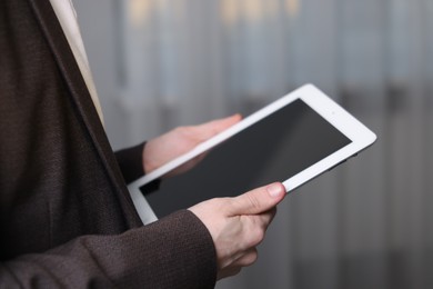 Photo of Businessman using tablet indoors, closeup. Modern technology