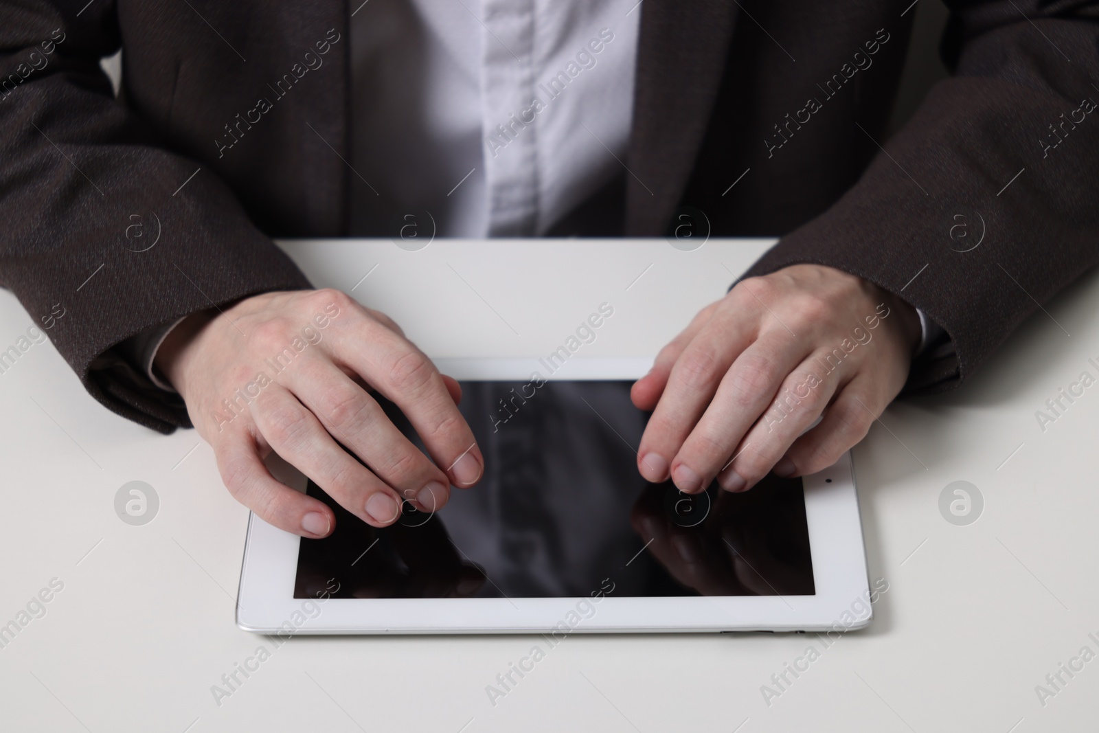 Photo of Businessman using tablet at white table, closeup. Modern technology