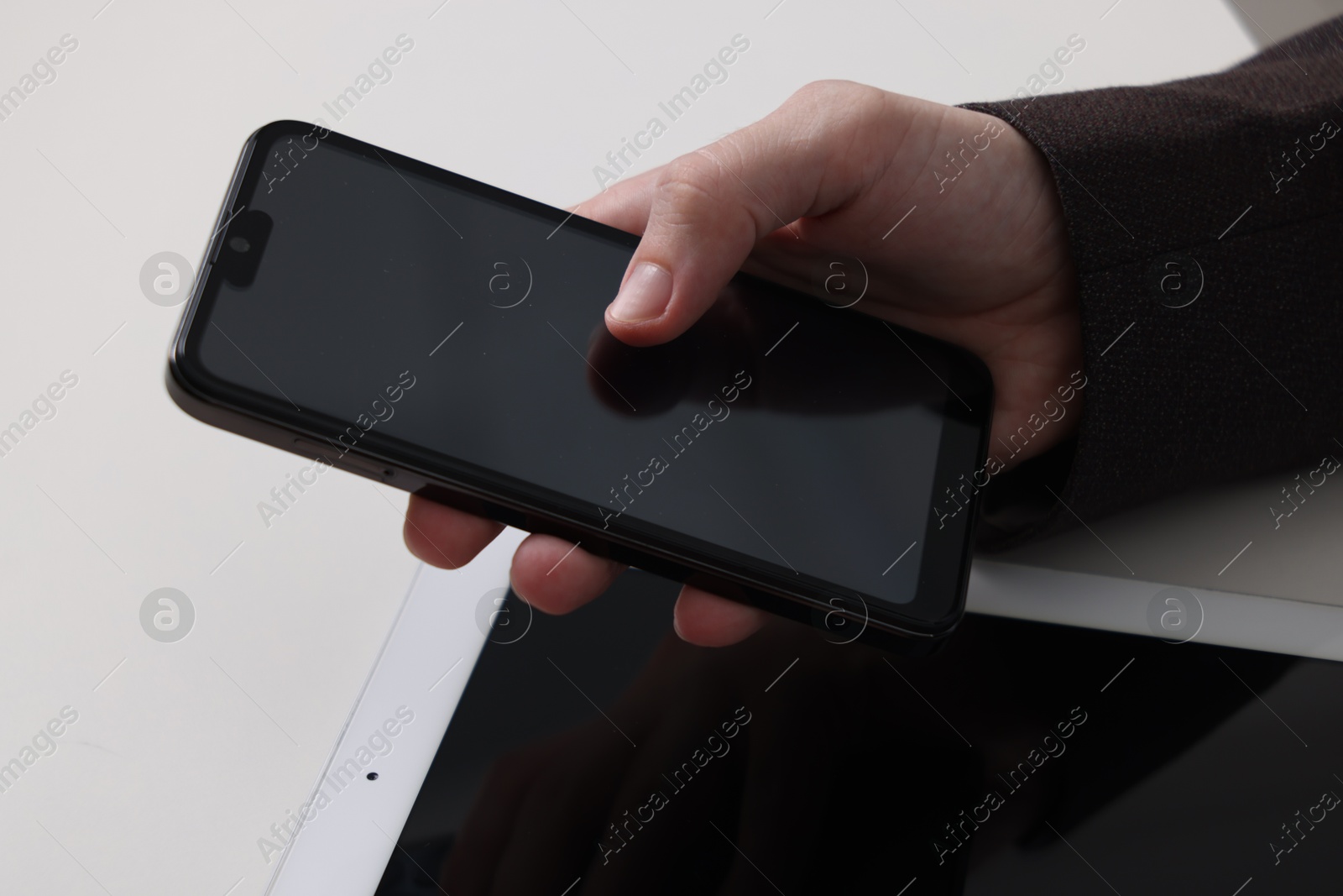 Photo of Businessman using smartphone at white table with tablet, closeup. Modern technology