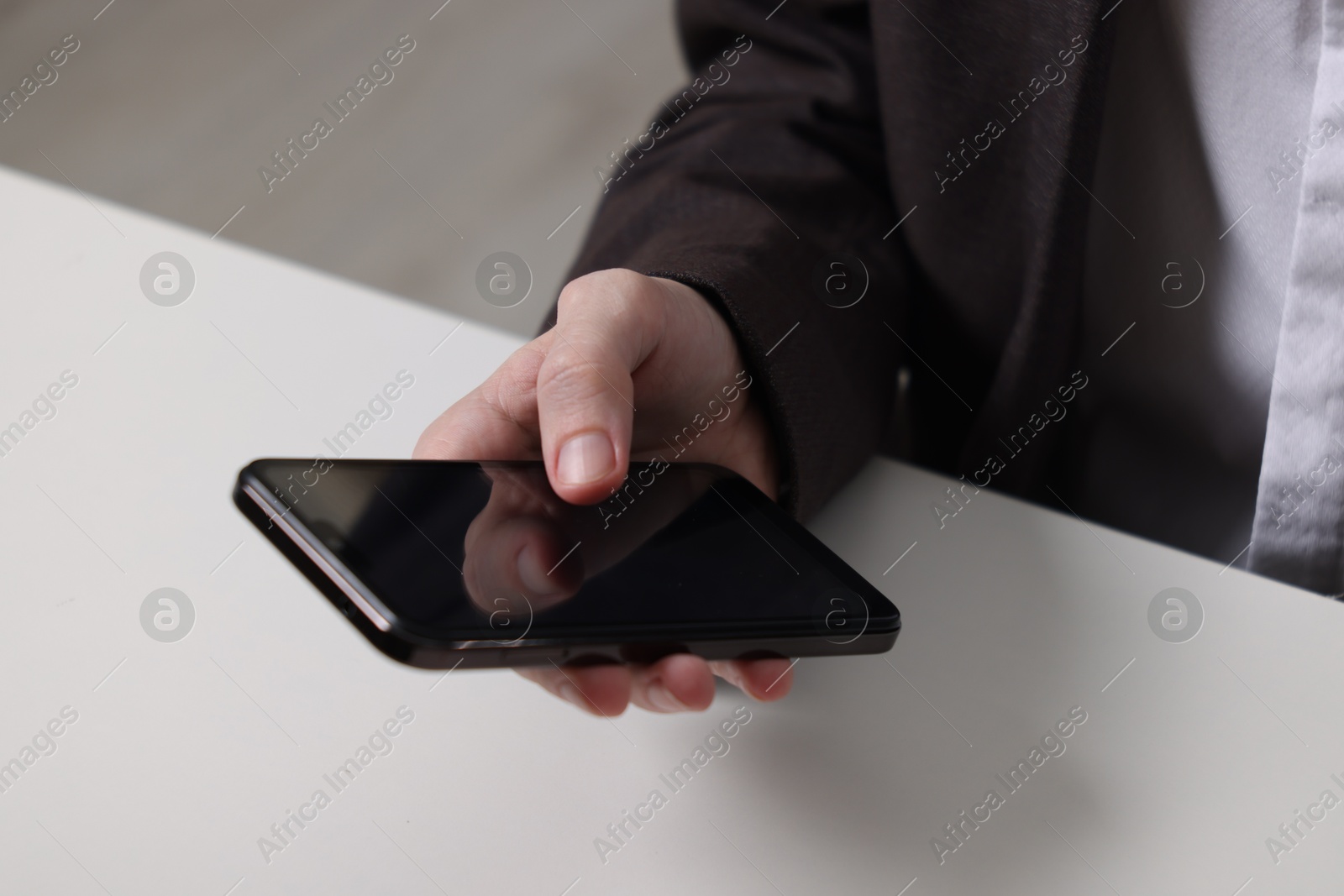 Photo of Businessman using smartphone at white table, closeup. Modern technology