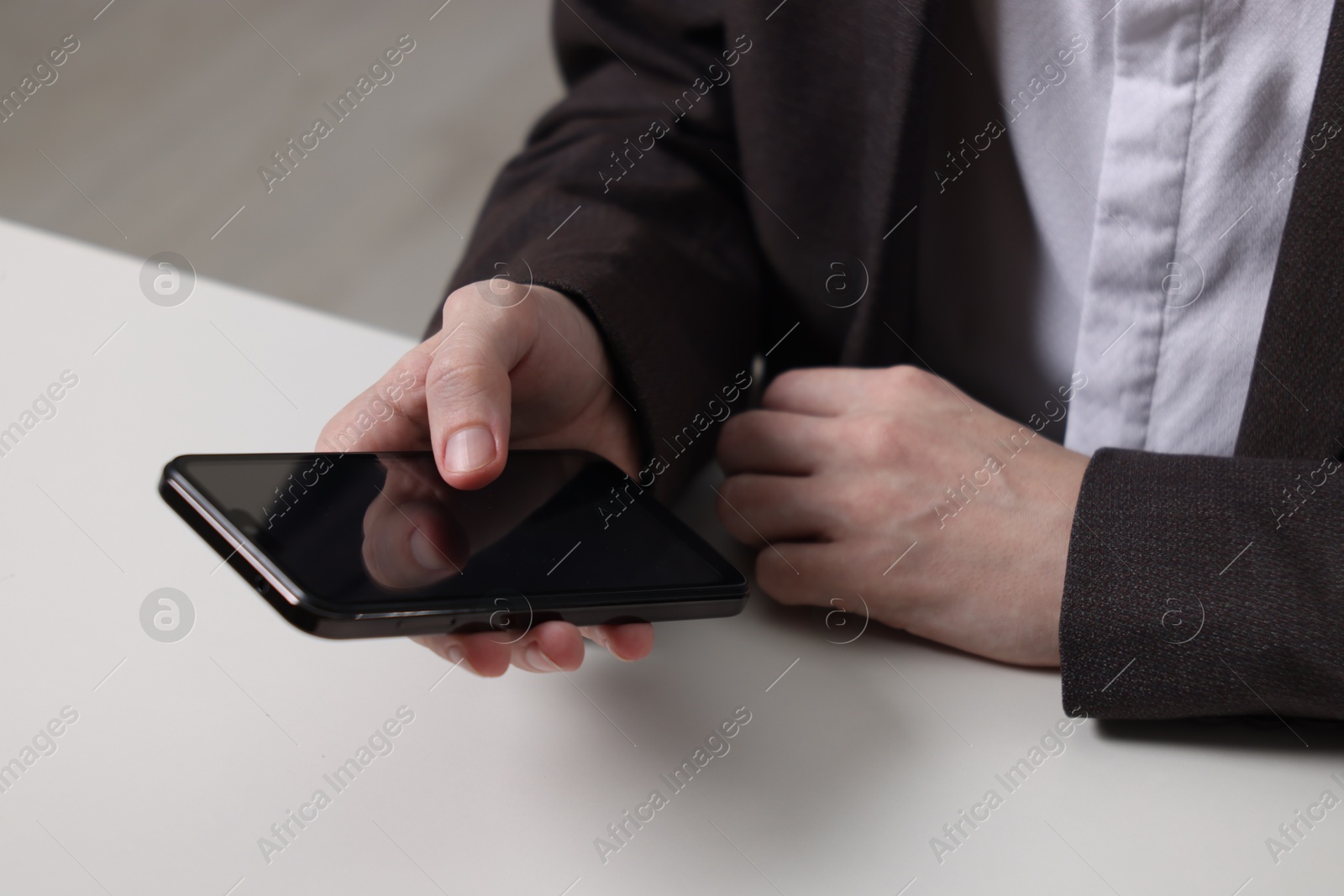 Photo of Businessman using smartphone at white table, closeup. Modern technology