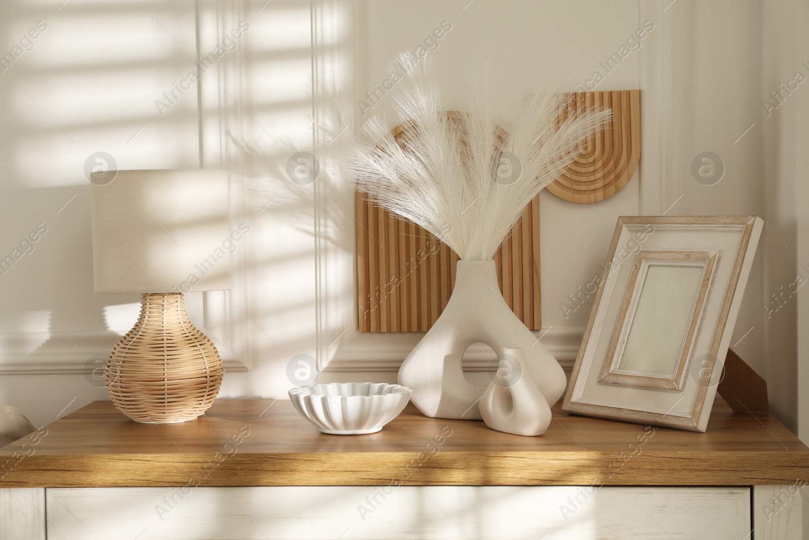 Photo of Beautiful decorative plants, vases, photo frame, ceramic bowl and lamp on wooden chest of drawers indoors