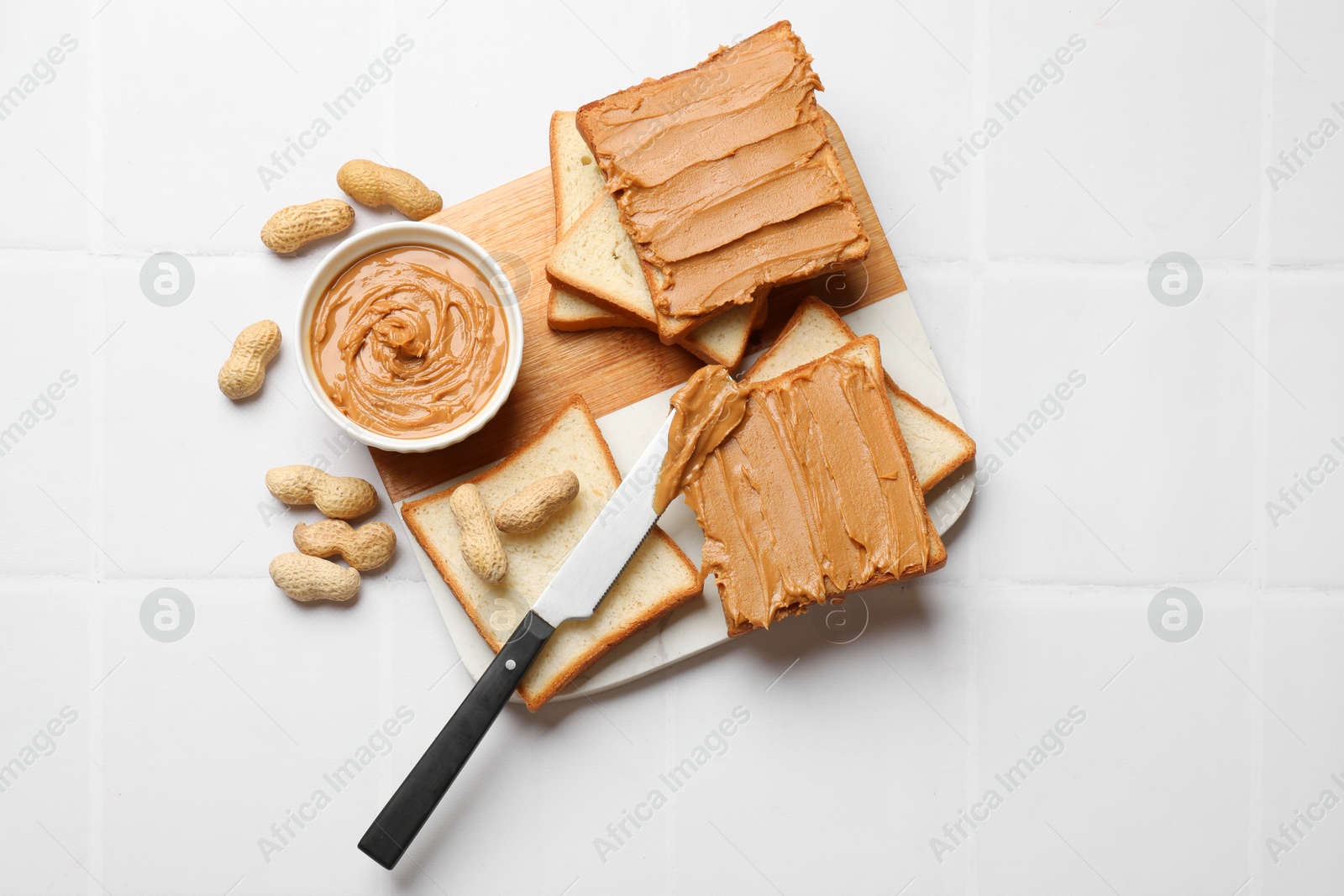 Photo of Delicious sandwiches with peanut butter and fresh nuts on white table, top view