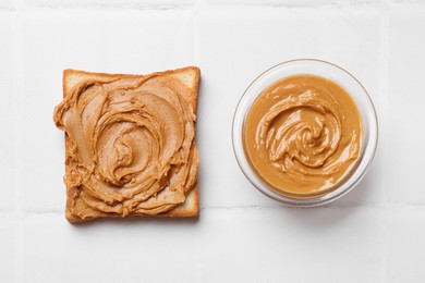 Photo of Delicious sandwich with peanut butter and tasty paste in bowl on white table, flat lay