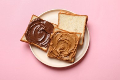 Photo of Delicious sandwiches with peanut butter and chocolate paste on pink table, top view