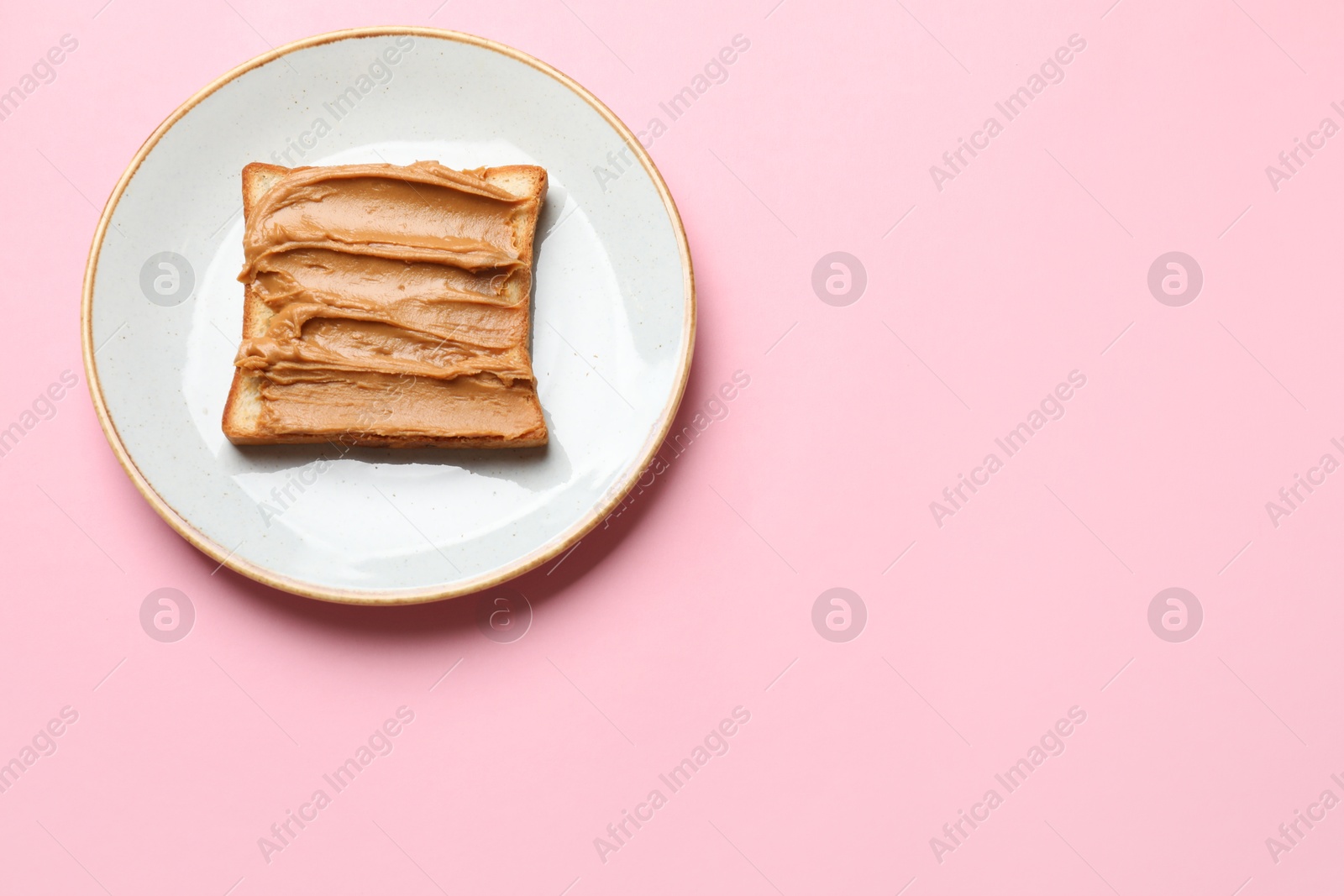 Photo of Delicious sandwich with peanut butter on pink table, top view. Space for text