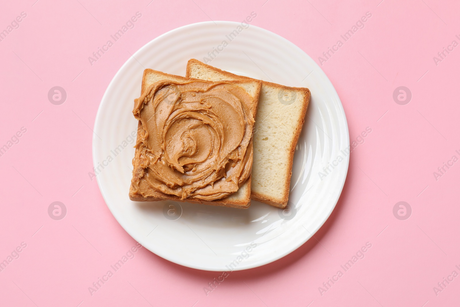 Photo of Delicious sandwich with peanut butter on pink table, top view