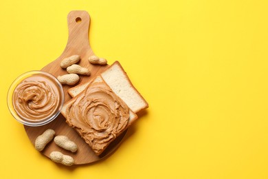 Photo of Delicious sandwich with peanut butter and fresh nuts on yellow table, top view. Space for text