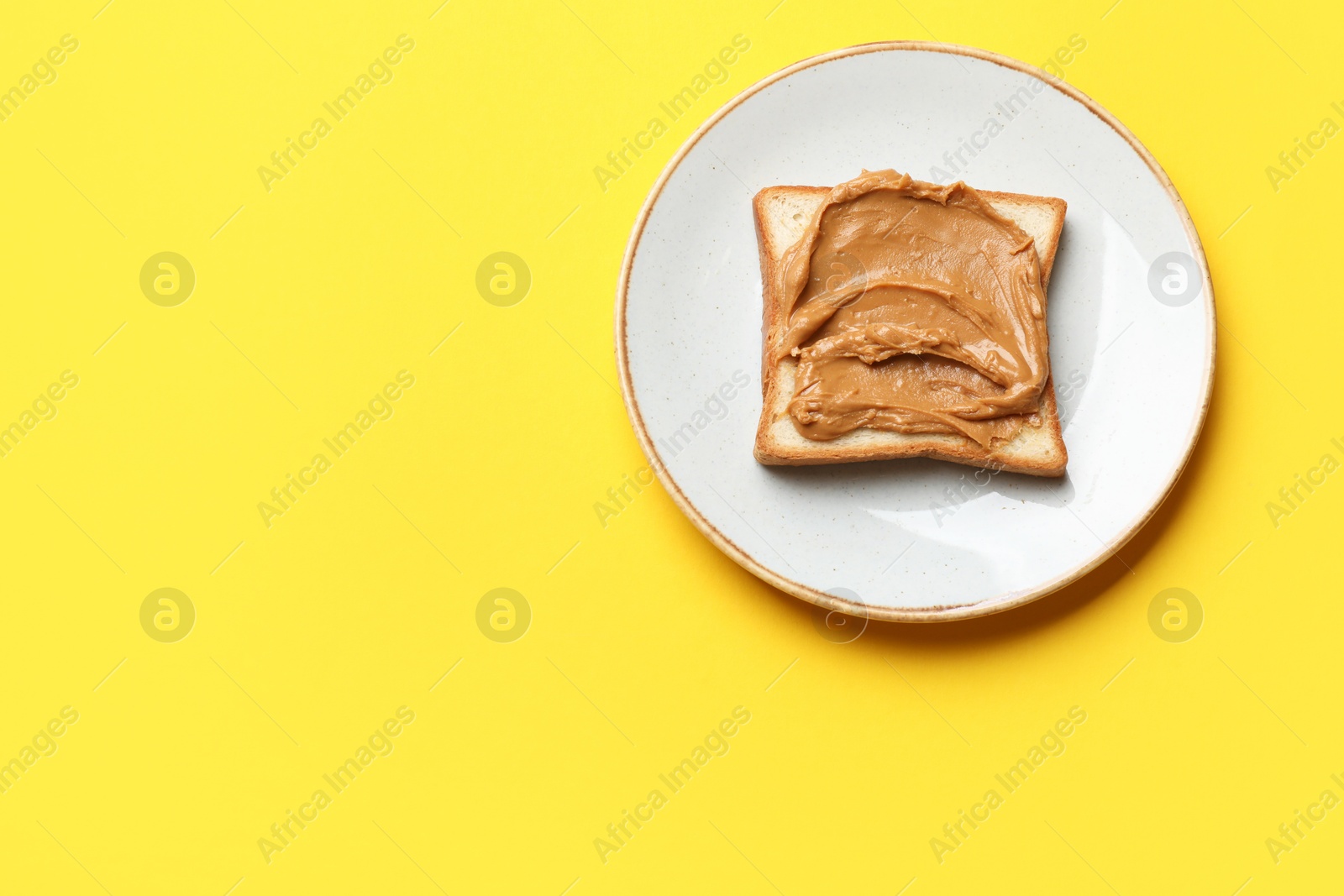 Photo of Delicious sandwich with peanut butter on yellow table, top view. Space for text