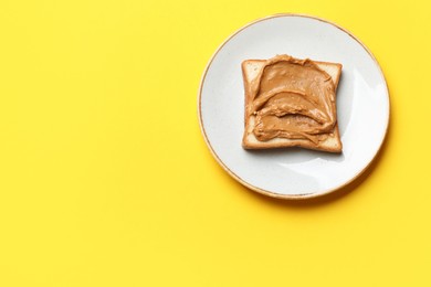 Delicious sandwich with peanut butter on yellow table, top view. Space for text