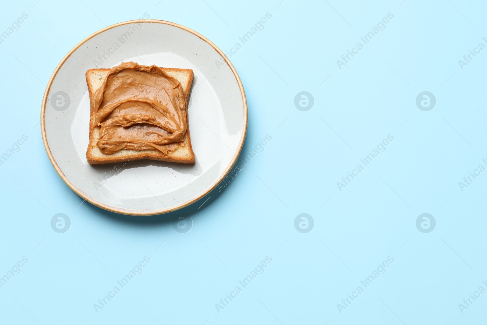 Photo of Delicious sandwich with peanut butter on light blue table, top view. Space for text