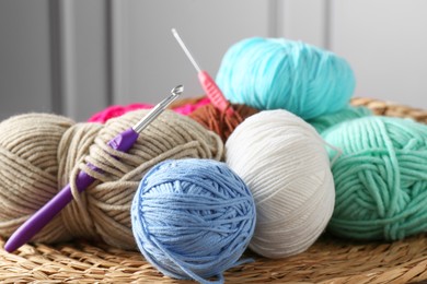 Photo of Different yarns and crochet hooks on wicker mat, closeup