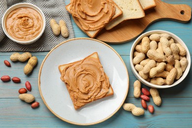 Photo of Tasty sandwiches with peanut butter and nuts on light blue wooden table, flat lay