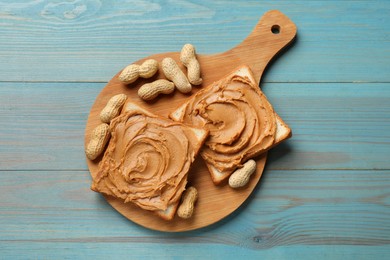 Photo of Tasty sandwiches with peanut butter and nuts on light blue wooden table, top view