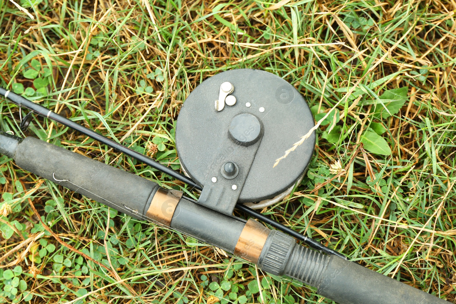 Photo of One fishing rod on green grass, top view