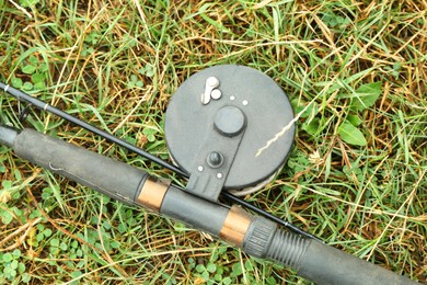 Photo of One fishing rod on green grass, top view