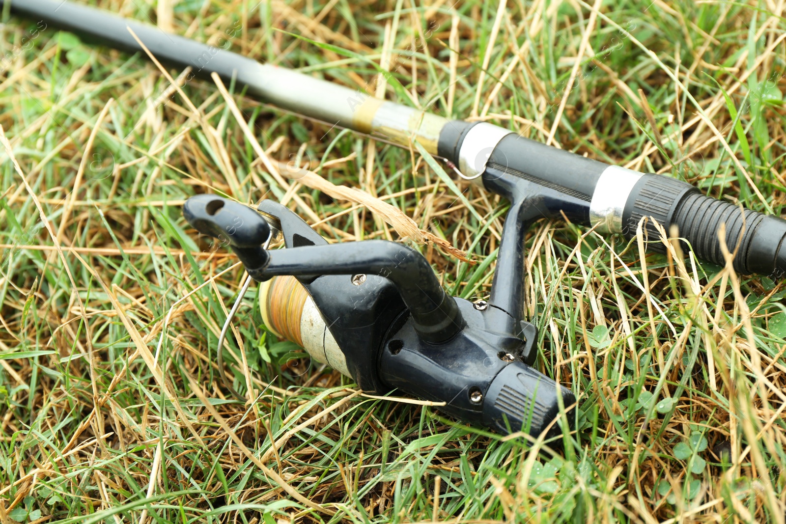 Photo of One fishing rod on green grass, closeup