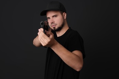 Photo of Young bodyguard using gun on black background