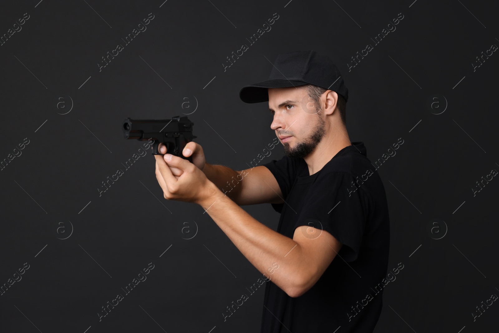 Photo of Young bodyguard using gun on black background