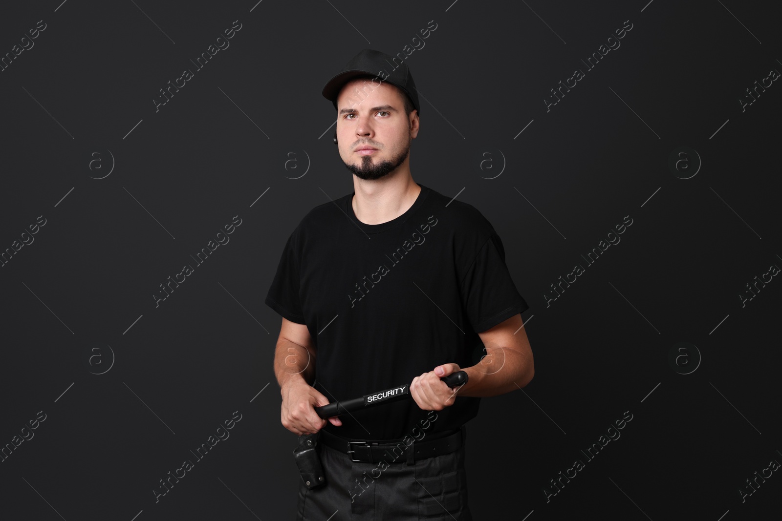 Photo of Young bodyguard with baton on black background