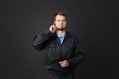 Photo of Security guard in uniform with earpiece and gun on black background