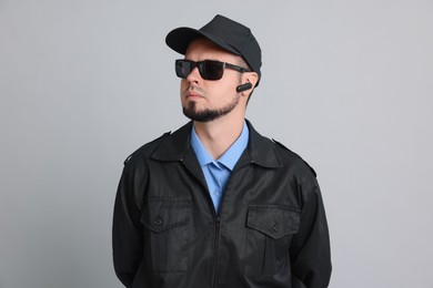 Security guard in uniform and sunglasses on grey background